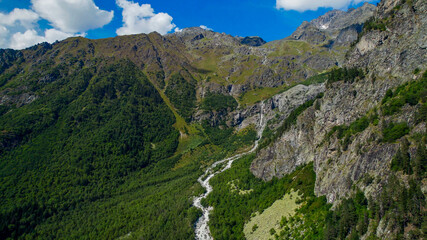 Breathtaking aerial view of a rugged mountain landscape with cascading river, embodying nature's...