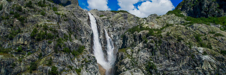 Majestic waterfall cascading down rugged cliffs against a clear blue sky, perfect for nature, travel themes, and Earth Day promotions
