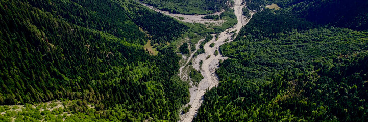 Aerial view of a meandering river cutting through a dense, green mountain valley, ideal for Earth...