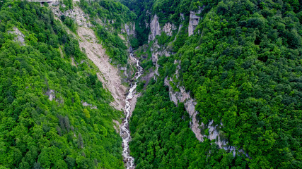 Aerial view of a lush green mountain gorge with a meandering river below, ideal for nature, adventure tourism, and environmental conservation concepts