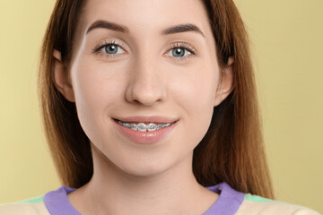 Portrait of smiling woman with dental braces on light green background, closeup