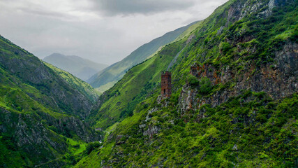 Panoramic view of misty green mountains with an ancient solitary tower, ideal for articles on hiking, nature conservation, and Earth Day backgrounds