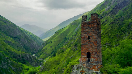 Panoramic view of misty green mountains with an ancient solitary tower, ideal for articles on...