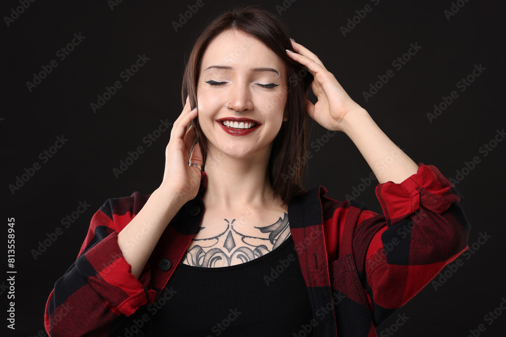 Poster Portrait of smiling tattooed woman on black background