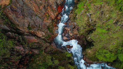 Aerial view of a vibrant forest river canyon with rushing water, ideal for nature and adventure...