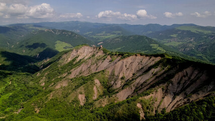 Breathtaking aerial view of a majestic green mountain range with unique rock formations under a...