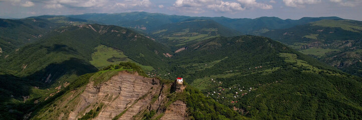 Aerial view of a solitary white house perched on a cliff overlooking green rolling hills and...