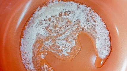 Bar of soap dissolving on a wet orange surface, symbolizing hygiene and cleanliness related to...