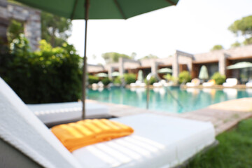 Sunbeds near swimming pool at luxury resort, blurred view