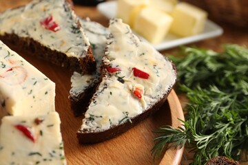 Tasty butter with dill, chili pepper and rye bread on table, closeup