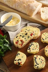Tasty butter with olives, chili pepper, parsley and bread on wooden table