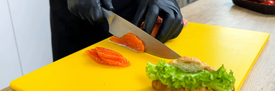 Close-up of chef slicing fresh salmon on a yellow cutting board for sushi preparation, conceptually related to culinary arts and healthy eating