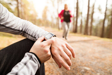 Overweight woman running down the stairs, personal trainer checking, timing her performance. Exercising outdoors for people with obesity, support from friend, fitness coach.