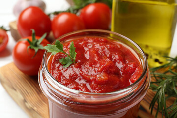 Homemade tomato sauce and parsley in jar on white table, closeup