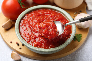 Eating homemade tomato sauce at light grey table, closeup