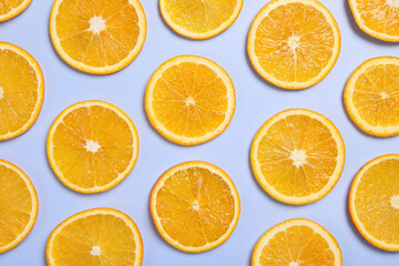 Fototapeta premium Slices of juicy orange on light blue background, flat lay