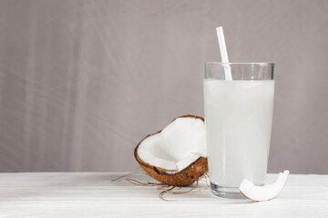 Glass of coconut water and nut on white wooden table. Space for text