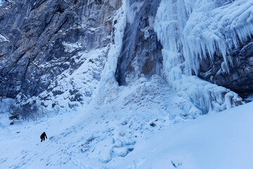 A person passing next to a partially frozen waterfall. Beautiful and magical winter holiday scenery...