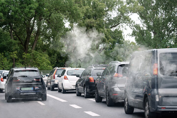 Environmental pollution. Air contaminated with fumes in city. Cars surrounded by exhaust on road