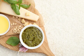 Tasty pesto sauce, basil, pine nuts, garlic, oil and cheese on light grey table, top view. Space for text