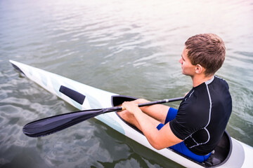 Canoeist man sitting in canoe holding paddle, in water. Concept of canoeing as dynamic and...