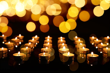 Many burning church candles in darkness, bokeh effect