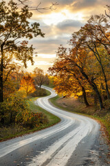 Fototapeta premium The warm glow of golden hour illuminating a winding rural road lined with trees. The minimalist composition, with just the road and colorful sky, conveys a sense of journey and adventure