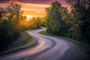 Naklejka premium The warm glow of golden hour illuminating a winding rural road lined with trees. The minimalist composition, with just the road and colorful sky, conveys a sense of journey and adventure