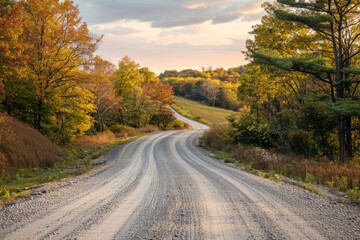 The warm glow of golden hour illuminating a winding rural road lined with trees. The minimalist composition, with just the road and colorful sky, conveys a sense of journey and adventure