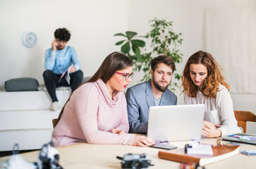 Obraz premium Young group of colleagues working on a new project together in a startup company office. Working in co-working space.