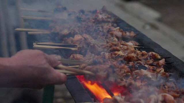 Hand flipping satay on traditional charcoal fire. Traditional barbecue. 