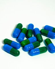 Vertical closeup shot of green and blue pills on the white background