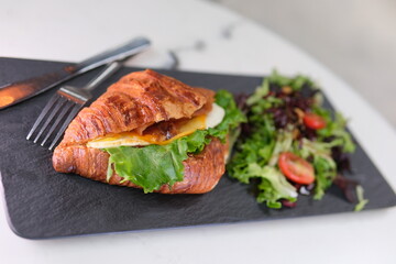 4K Breakfast Scene. A woman is eating a croissant with bacon and scrambled eggs at breakfast.
