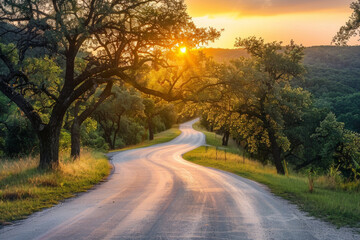 Fototapeta premium The warm glow of golden hour illuminating a winding rural road lined with trees. The minimalist composition, with just the road and colorful sky, conveys a sense of journey and adventure