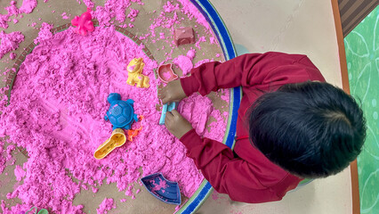 Indonesian boy playing kinetic sand in indoor room