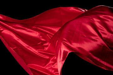 Red Satin fabric flying in curve shape, Piece of textile Red Satin fabric throw fall in air. Black...
