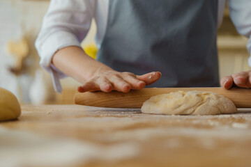 Woman hands is rolling the dough on the kitchen table