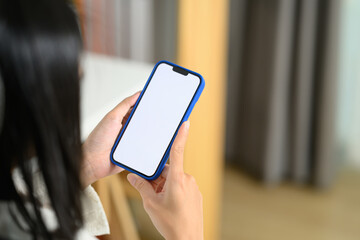 Over shoulder view of woman holding smartphone with blank screen sitting in office