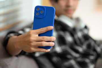 Select focus on hand of hipster man holding smartphone, scrolling and texting in social networks