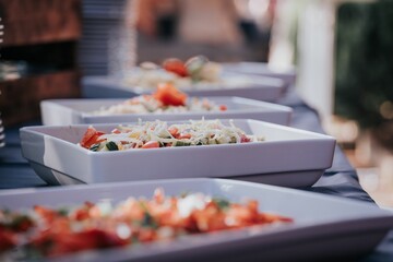 Selective focus of salads in white bowls in a row on a banquet table