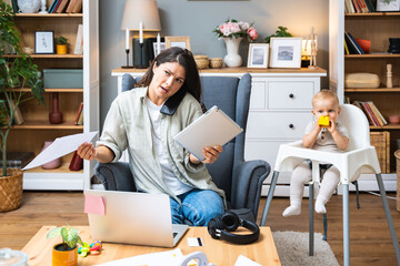Multitasking mother. Young freelance business mom taking care of her child, young baby, and working...