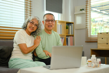 Cheerful senior couple in video conferencing with general practitioner on laptop. Telehealth concept