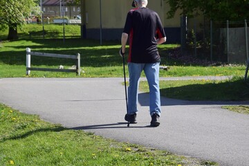 A senior with a Scandinavian stick walks along a city street. Active lifestyle in old age.
