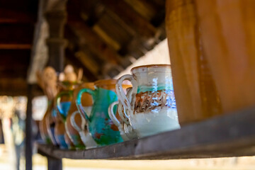 Selective focus of beautiful, colorful ceramic jugs on the wooden shelf of the shop