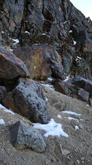 Vertical closeup of stones on the sand, snow around