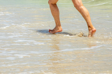 feet of attractive mature woman running at the beach in the water