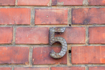 house number five at an old brick wall
