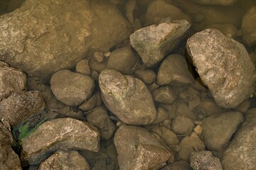 Closeup shot of the big rocks in the clear river water