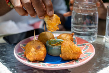Closeup of a hand dipping delicious Barbadian fishcakes in sauce