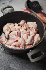 Chicken wings cooking in a pan with wooden spoons nearby